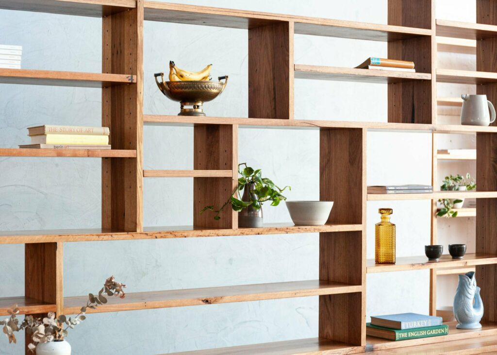 timber bookshelf with plants and glassware